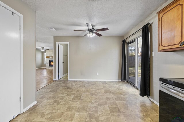 1324 Annette Dr, Longview, TX 75604 - unfurnished dining area with ceiling fan, a textured ceiling, baseboards, and a fireplace