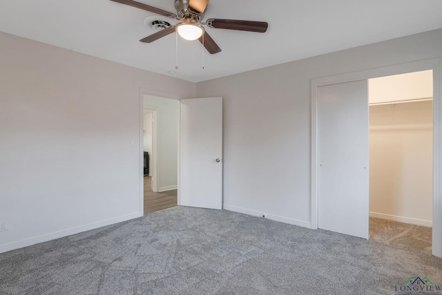 unfurnished bedroom featuring a walk in closet, carpet floors, a closet, and ceiling fan