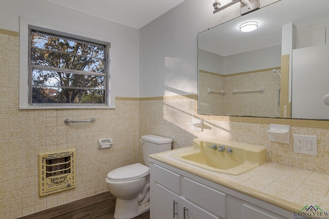 bathroom featuring vanity, toilet, tile walls, wood-type flooring, and heating unit