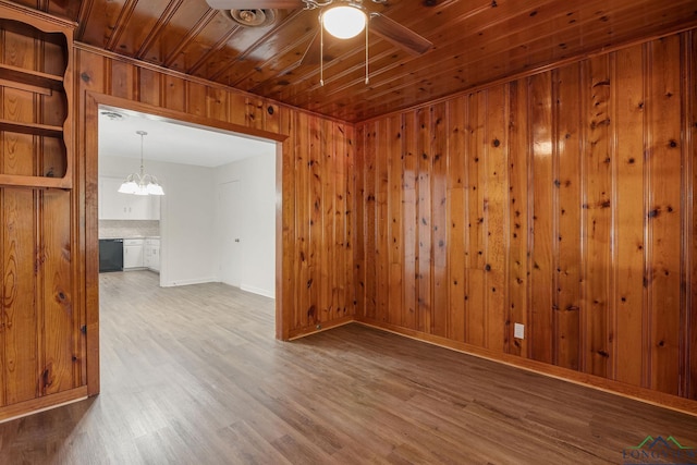 unfurnished room featuring ceiling fan with notable chandelier, wood-type flooring, wooden walls, and wooden ceiling