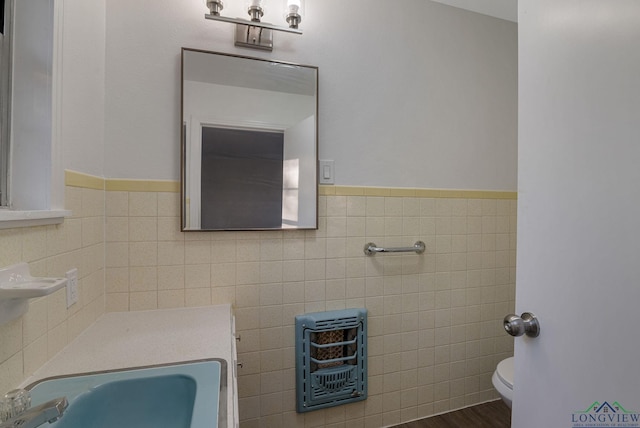 bathroom featuring sink, hardwood / wood-style flooring, toilet, tile walls, and heating unit