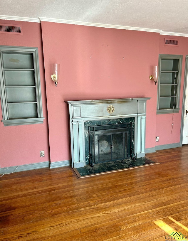 interior details with built in shelves, ornamental molding, a premium fireplace, and hardwood / wood-style flooring