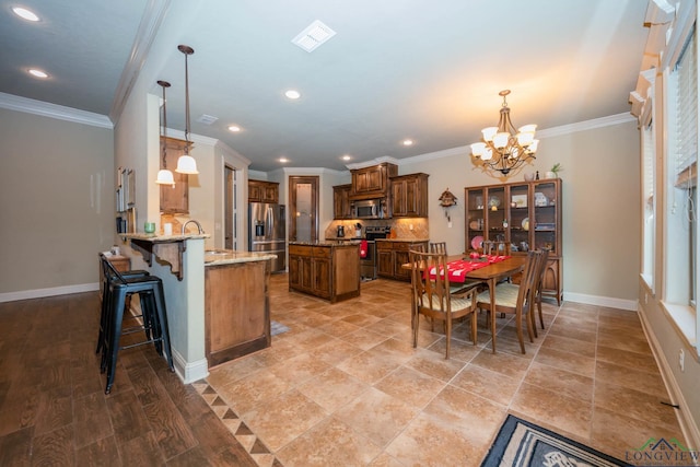 kitchen featuring kitchen peninsula, appliances with stainless steel finishes, a breakfast bar, pendant lighting, and a chandelier