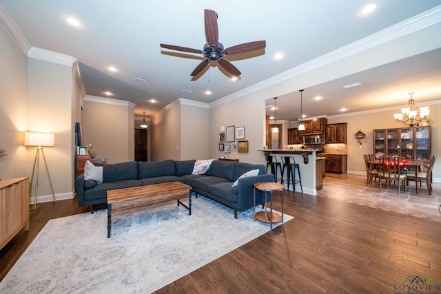 living room featuring dark hardwood / wood-style flooring, ceiling fan with notable chandelier, and ornamental molding