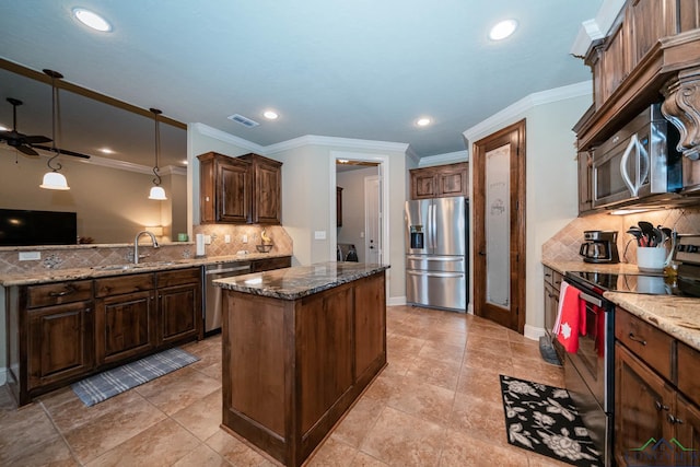 kitchen with dark stone counters, hanging light fixtures, sink, ceiling fan, and stainless steel appliances