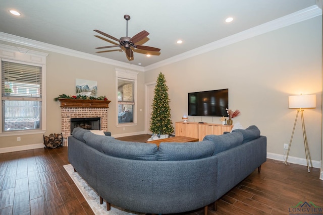 living room featuring ceiling fan, dark wood-type flooring, ornamental molding, and a brick fireplace