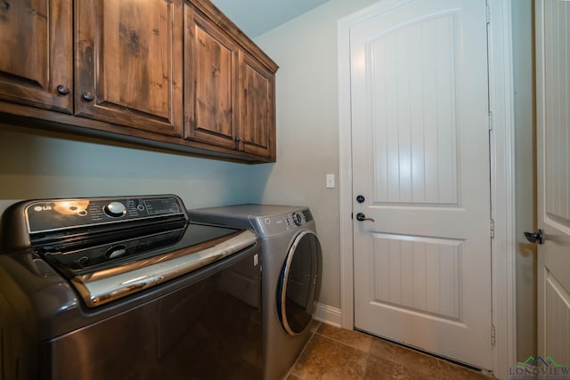 laundry room with cabinets, dark tile patterned floors, and washing machine and clothes dryer