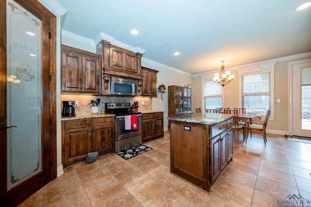 kitchen featuring light stone counters, stainless steel appliances, decorative light fixtures, a notable chandelier, and a center island