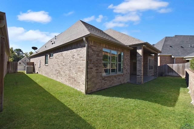 rear view of house with central AC unit, a patio area, and a yard