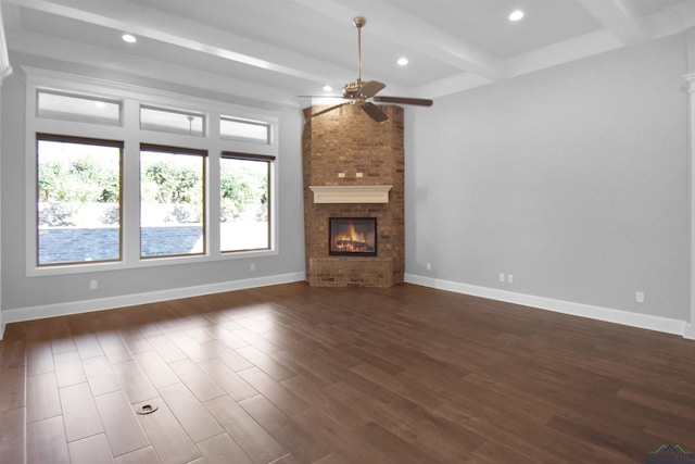 unfurnished living room featuring beam ceiling, dark hardwood / wood-style flooring, a brick fireplace, and ceiling fan