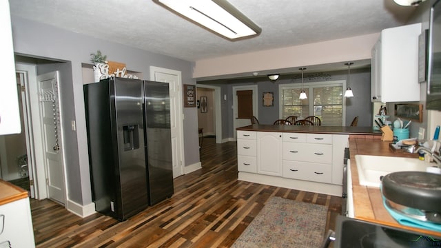 kitchen with white cabinetry, refrigerator with ice dispenser, kitchen peninsula, a textured ceiling, and decorative light fixtures