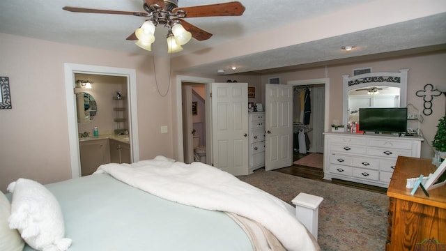 bedroom featuring ensuite bath, ceiling fan, a spacious closet, dark hardwood / wood-style flooring, and a closet