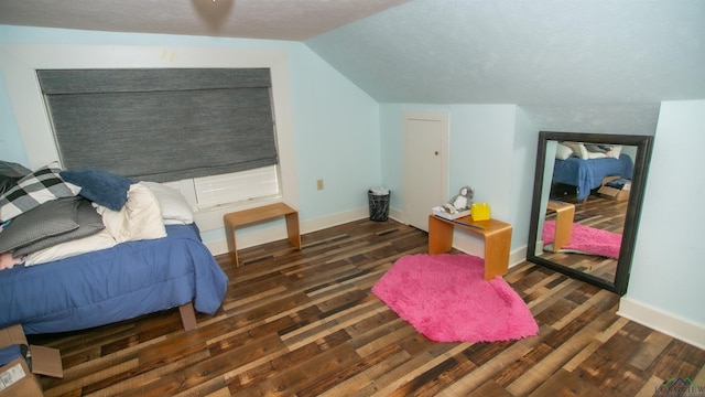 bedroom with a textured ceiling, dark hardwood / wood-style flooring, and vaulted ceiling