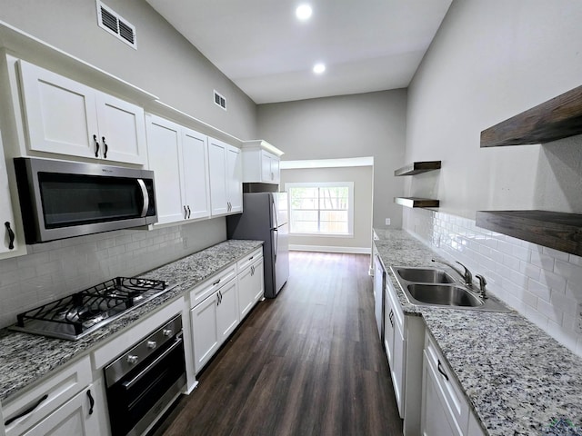 605 E Rusk St, Marshall, TX 75670 - kitchen featuring appliances with stainless steel finishes, a sink, open shelves, dark wood-style floors, and white cabinets