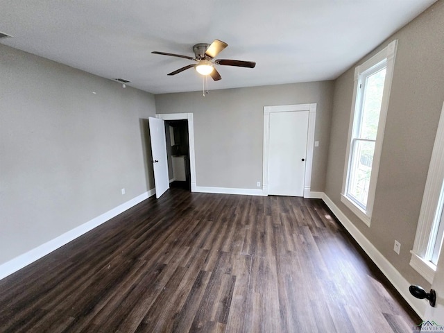 605 E Rusk St, Marshall, TX 75670 - unfurnished bedroom with dark wood-style flooring, multiple windows, and baseboards