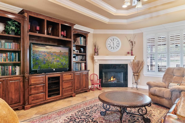 living room with a fireplace, ceiling fan, ornamental molding, and a tray ceiling