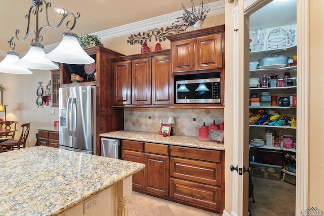 kitchen featuring stainless steel appliances, light stone counters, backsplash, hanging light fixtures, and crown molding