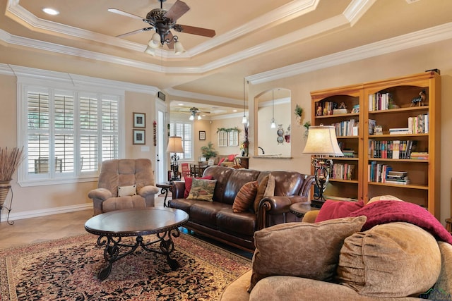 tiled living room with ceiling fan, crown molding, and a raised ceiling