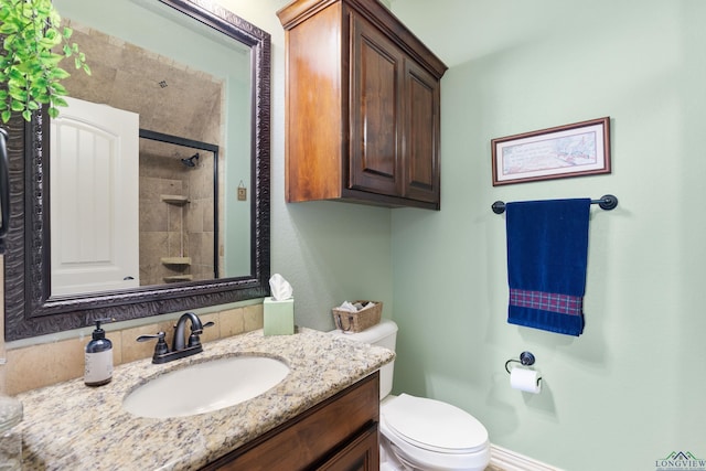 bathroom featuring a shower with door, vanity, and toilet