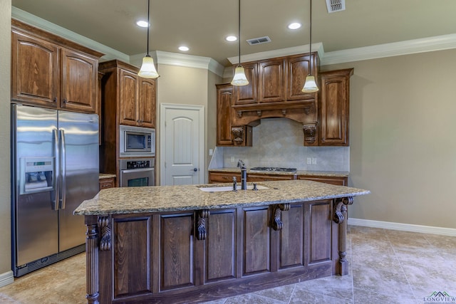 kitchen featuring sink, decorative light fixtures, appliances with stainless steel finishes, an island with sink, and light stone countertops