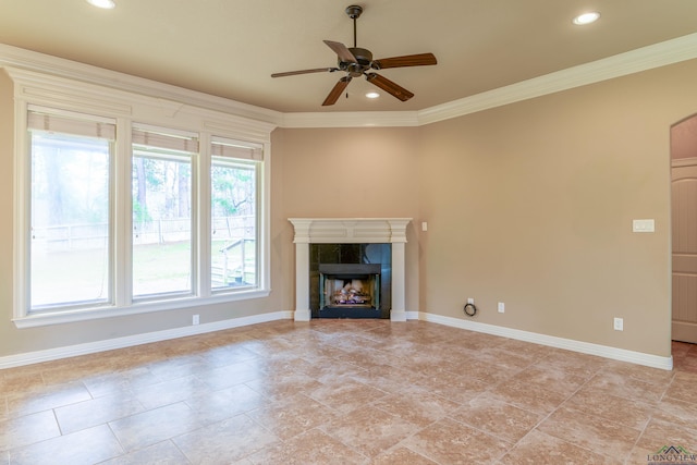 unfurnished living room with a tile fireplace, ornamental molding, and ceiling fan