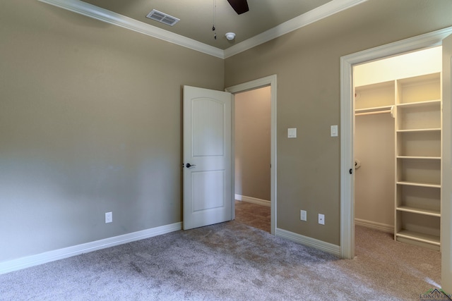 unfurnished bedroom featuring light carpet, a closet, a spacious closet, and crown molding