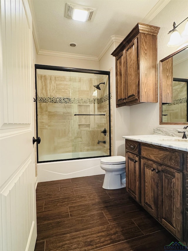 full bathroom featuring toilet, bath / shower combo with glass door, crown molding, and vanity