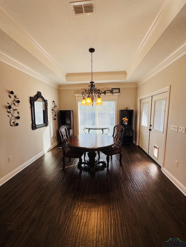 dining room with dark hardwood / wood-style floors, an inviting chandelier, crown molding, and a raised ceiling