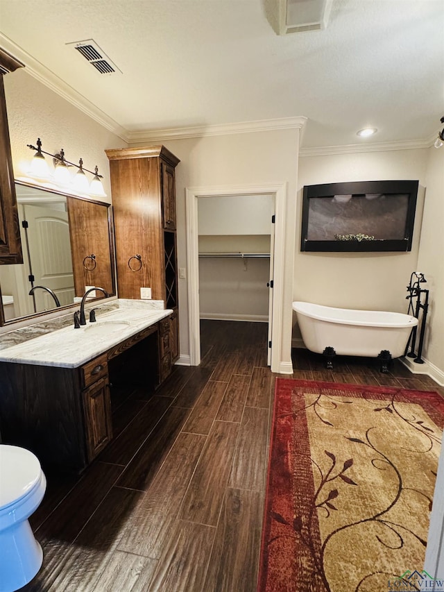 bathroom featuring toilet, vanity, a bathing tub, and ornamental molding