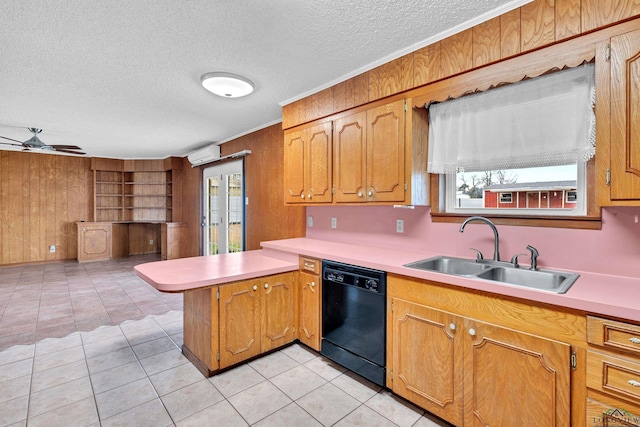 kitchen with wooden walls, light countertops, black dishwasher, a peninsula, and a sink