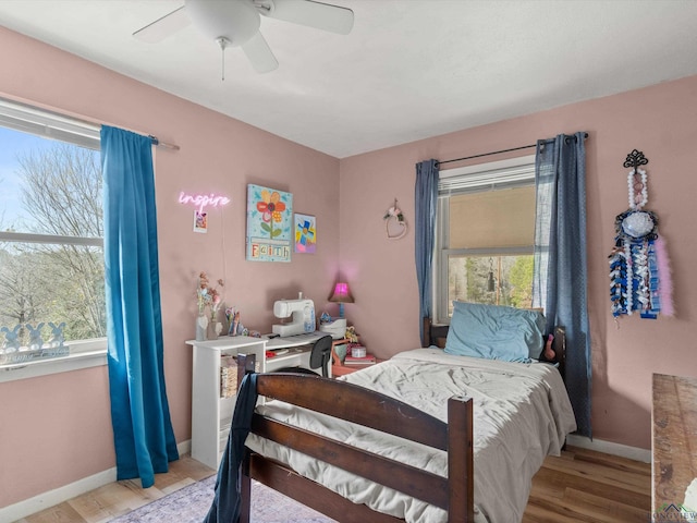 bedroom with ceiling fan, multiple windows, and light hardwood / wood-style flooring