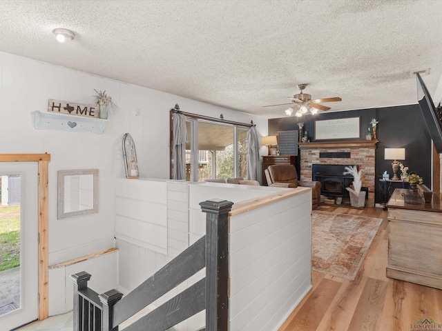 interior space featuring ceiling fan, a wood stove, a textured ceiling, and light hardwood / wood-style flooring