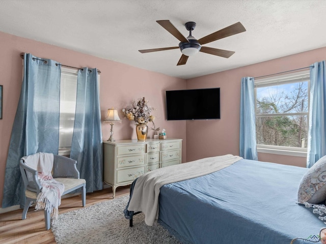 bedroom with ceiling fan, a textured ceiling, and light wood-type flooring