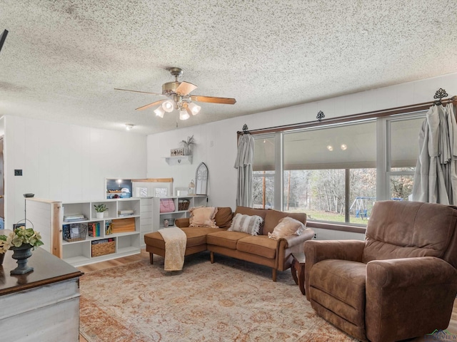 living room featuring hardwood / wood-style flooring, ceiling fan, and a textured ceiling