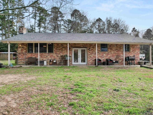 rear view of house with a patio, a lawn, and french doors