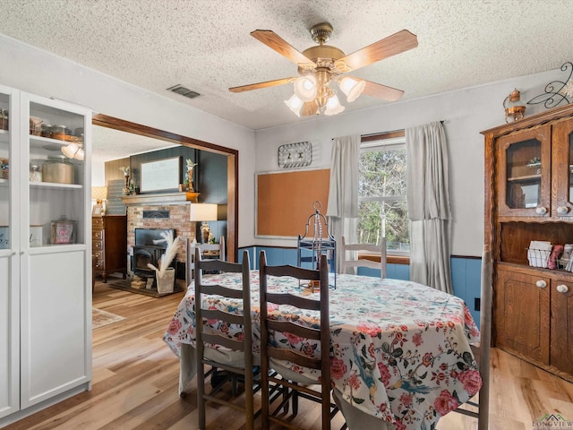 dining area with ceiling fan, a textured ceiling, and light hardwood / wood-style floors