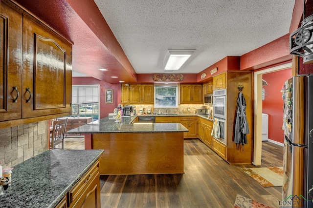 kitchen featuring appliances with stainless steel finishes, tasteful backsplash, sink, dark hardwood / wood-style floors, and a kitchen island