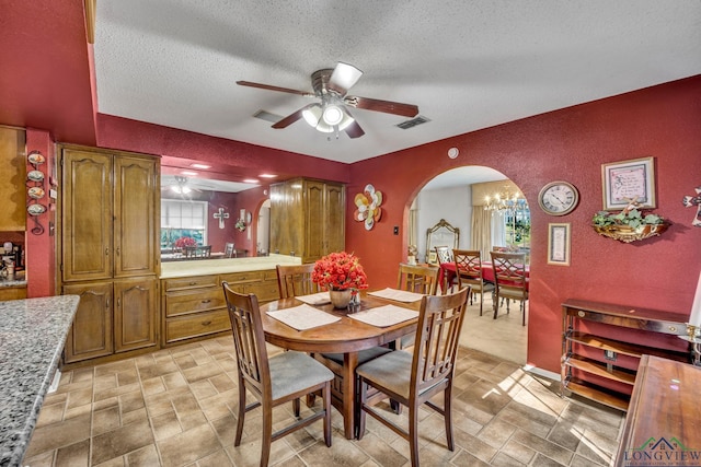 dining area featuring ceiling fan with notable chandelier, a textured ceiling, and a wealth of natural light