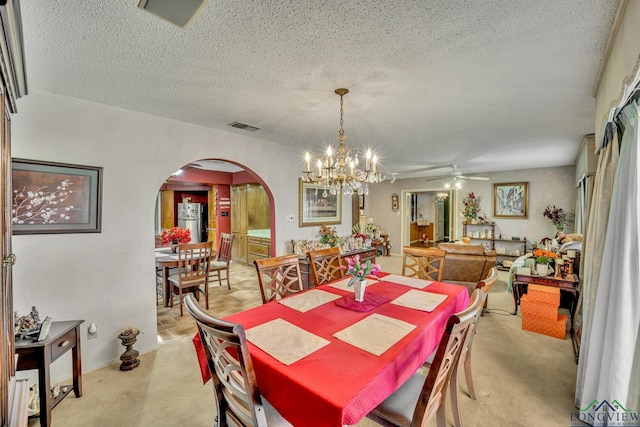 carpeted dining area with a textured ceiling and ceiling fan with notable chandelier