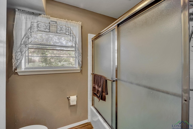 bathroom with bath / shower combo with glass door and toilet