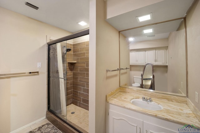 bathroom featuring tile patterned floors, vanity, toilet, and walk in shower