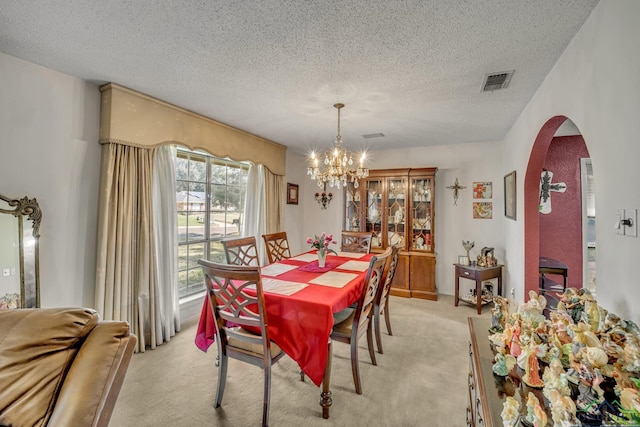 carpeted dining room with a chandelier and a textured ceiling