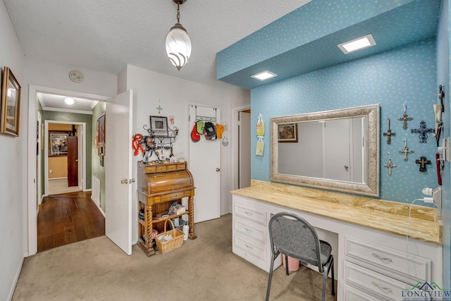 carpeted office featuring crown molding, built in desk, and a textured ceiling