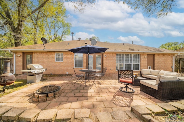 rear view of house with brick siding, a patio area, an outdoor living space with a fire pit, and fence