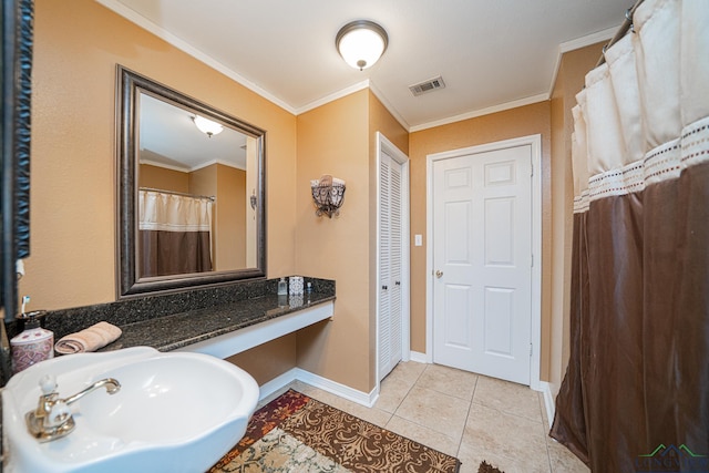 bathroom featuring tile patterned floors, visible vents, ornamental molding, a sink, and baseboards
