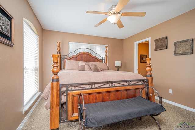 carpeted bedroom featuring baseboards, ceiling fan, and multiple windows