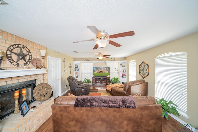 living area featuring wood finished floors, a ceiling fan, baseboards, and a fireplace