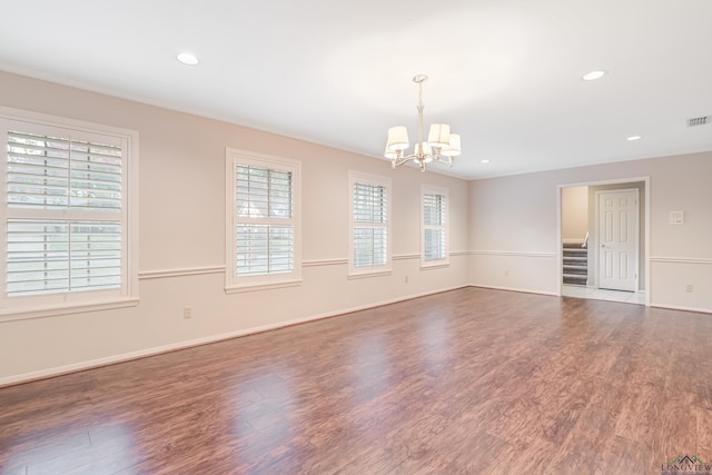 empty room with dark hardwood / wood-style flooring and a notable chandelier