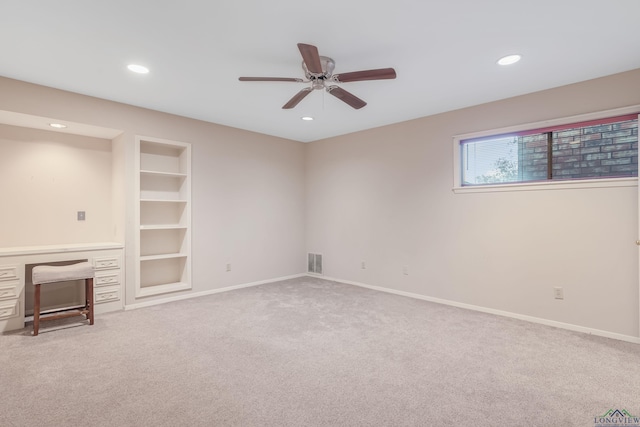 unfurnished living room with built in shelves, ceiling fan, and carpet