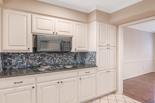 kitchen with white cabinets, tasteful backsplash, dark stone counters, and black appliances